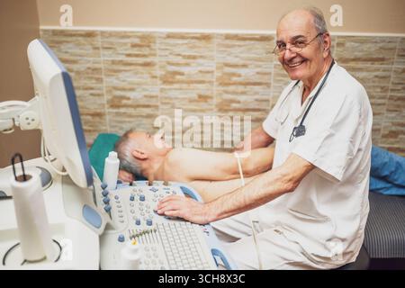 Kardiologe, der ein Echokardiogramm an einem älteren Patienten mit Ultraschallgeräten zur Diagnose von Brustschmerzen und Hypertonie durchführt. Stockfoto