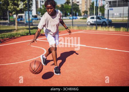 Afrikanische Basketballspielerin, die während eines Solo-Workouts Dribbling-Fähigkeiten übt. Stockfoto