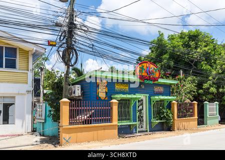 Isla de Roatan, Honduras - 16. April 2024: Straßenblick von Roatan mit Touristenläden und zahlreichen Drähten am Pol auf Roatan Island, Honduras. Stockfoto