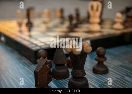 Nahaufnahme antiker hölzerner Schachfiguren, die strategisch auf einem karierten Brett positioniert sind, was die intellektuelle Herausforderung und den zeitlosen Reiz von unterstreicht Stockfoto