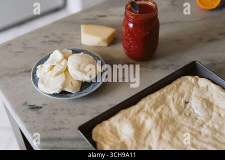 Pizza-Vorbereitung am Abend mit frischem Mozzarella und Tomatensauce Stockfoto