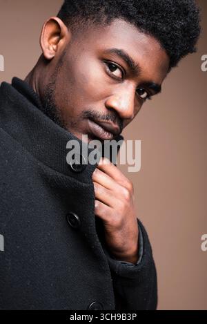 Nahaufnahme eines eleganten afrikanischen Mannes in schwarzer Jacke, der in die Kamera schaut Stockfoto