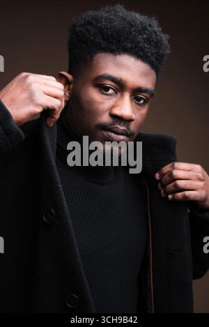 Nahaufnahme eines eleganten afrikanischen Mannes in schwarzer Jacke, der in die Kamera schaut Stockfoto