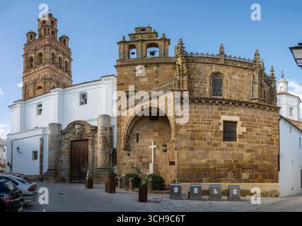 Historische Kathedrale von Llerena mit einer Mischung aus architektonischen Stilen, mit einer Steinfassade, einem Glockenturm und einem bogenförmigen Eingang, der in einem klaren Blau steht Stockfoto