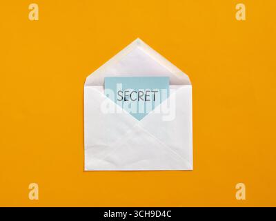 Geheime Nachricht aus einem weißen Umschlag auf orangem Hintergrund, Konzept vertraulicher Informationen Stockfoto