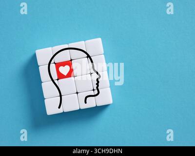 Menschliche Kopf Silhouette mit rotem Herz auf weißer Würfel Struktur auf blauem Hintergrund. Liebe im Sinn. Liebe und das Gehirn. Stockfoto