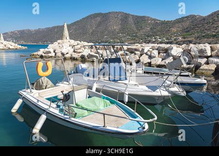 Weiße Fischerboote, die an einem warmen Sommertag unter der Sonne am Pier im Hafen von Pomos, Zypern, ankern und eine ruhige Küstenlandschaft schaffen Stockfoto