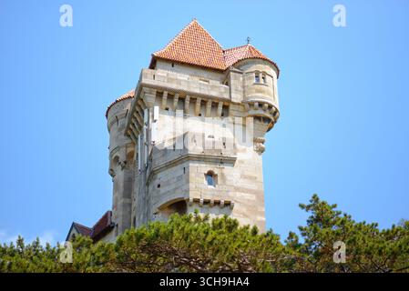 Maria Enzersdorf, Österreich - 24. Juli 2021: Nahaufnahme eines mittelalterlichen Steinturms mit rotgekachelten Dächern der Burg Liechtenstein vor einem klaren B Stockfoto