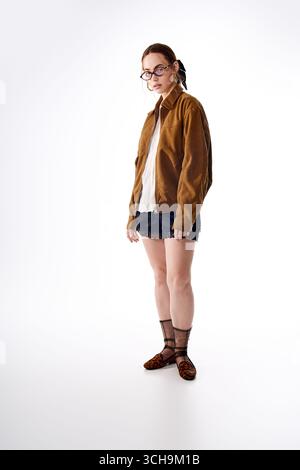 Eine junge Frau steht selbstbewusst in einem stilvollen Outfit, das moderne Trends mit Eleganz verbindet. Stockfoto