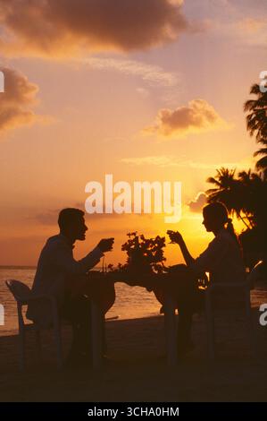 Malediven. Junges Paar beim Abendessen am tropischen Strand bei Sonnenuntergang. Stockfoto