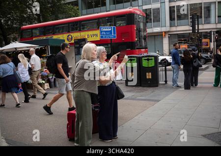 Touristen mittleren Alters sehen sich eine Straßenkarte der Gegend an, während sie an einer Straßenecke im Zentrum von London, England, Großbritannien, halten Stockfoto