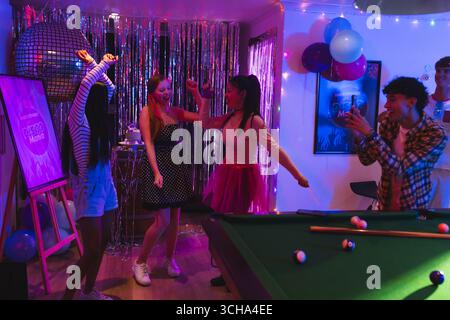 Teenager vielfältige Freunde tanzen fröhlich auf der Heimparty mit Discoball und Ballons. Feiern, tanzen, Jugend, Spaß, Musik, Freunde Stockfoto