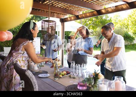 Verschiedene Seniorenfreunde feiern im Freien, teilen sich Lachen und Getränke am Pool. Party, Sozialisierung, Glück, draußen, Entspannung, Gat Stockfoto
