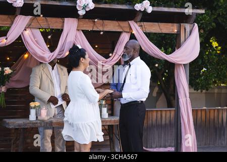 Bei der Hochzeit tauscht das Ehepaar unter einem romantischen Blumenbogen das Gelübde aus und feiert im Garten. Hochzeit, Romantik, Engagement, Zeremonie, Hochzeit, Stockfoto