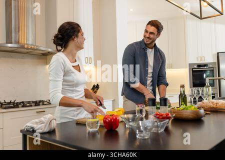 Paare, die gemeinsam in der modernen Küche essen, lächeln und unterhalten, zu Hause. Kochen, Zweisamkeit, häuslich, Lifestyle, kulinarisch, in Stockfoto