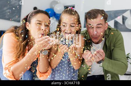 Gemeinsam feiern, bunte Konfetti mit der Familie ausblasen, fröhliche Momente drinnen teilen. Feiern, Spaß, Zweisamkeit, Glück, festlich, Party Stockfoto