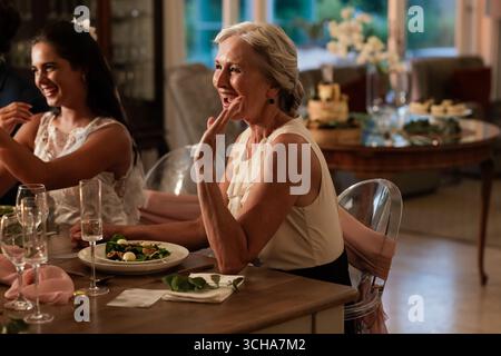 Ältere Frau, die bei Hochzeitsempfang freudig toast, Abendessen mit der Familie genießt. Feiern, Glück Stockfoto