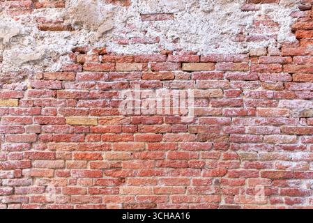 Rustikale Backsteinmauerstruktur mit warmen Erdtönen, verwitterter Oberfläche und natürlichen Mängeln, ideal für Hintergründe, Vintage-Projekte, oder Architectu Stockfoto