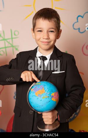 Glücklicher Student, der eine Kugel hält. Lächelnder Junge mit einer Kugel. Geografie-Lektion Stockfoto