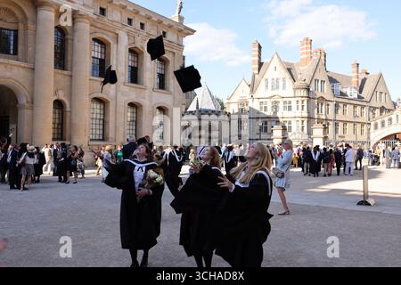 Studenten werfen ihre Mörteltafeln in die Luft, um den Abschluss zu feiern, vor dem Sheldonian Theatre, Oxford University, Oxfordshire, Großbritannien Stockfoto