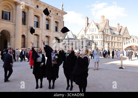 Studenten werfen ihre Mörteltafeln in die Luft, um den Abschluss zu feiern, vor dem Sheldonian Theatre, Oxford University, Oxfordshire, Großbritannien Stockfoto