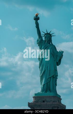 Aus nächster Nähe die Freiheitsstatue auf Liberty Island, New York City, die Fackel hielt hoch vor einem hellen Himmel. Stockfoto