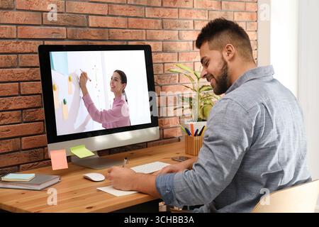 E-Learning-Konzept. Schüler, der Online-Videochat mit dem Lehrer über einen Computer am Schreibtisch führt Stockfoto