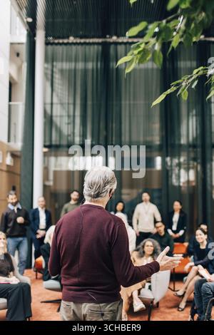 Rückansicht eines hochrangigen männlichen Delegierten, der beim Gipfel im Kongresszentrum vor Unternehmern spricht Stockfoto