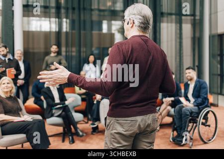 Rückansicht eines männlichen Senior-Delegierten, der Ideen erklärt, während er eine Rede vor Unternehmern beim Gipfel im Kongresszentrum hält Stockfoto