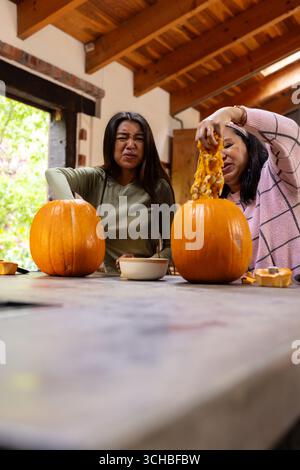 Halloween-Zeit, Oma und asiatische Teenager schnitzen zusammen Kürbisse, zu Hause. halloween, Tradition, Familie, festlich, verbunden, feiern Stockfoto