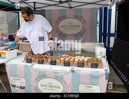 Ein Verkäufer an einem Straßenmarkt verkauft handgemachte Pralinen und Kuchen mit verschiedenen köstlichen Gebäckstücken. Stockfoto