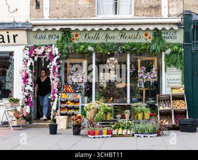 Blick auf die Straße auf ein bezauberndes Blumengeschäft bat Spa Floristen mit farbenfrohen Blumendekorationen, Topfpflanzen und einem einladenden, mit Grün geschmückten Eingang Stockfoto