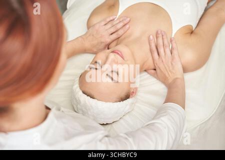 Junge kaukasische Frau genießt entspannende Spa-Massage-Behandlung mit professioneller Therapeutin. Stockfoto