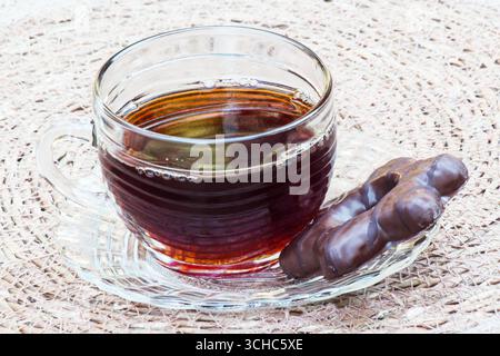 Eine Tasse Kaffee mit einem Schokoladenkeks auf einer rustikalen Tischmatte Stockfoto