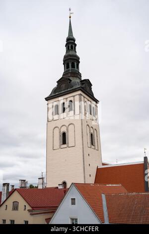 Historischer Kirchturm mit grünem Kupferturm, der sich über den traditionellen roten Ziegeldächern in der Altstadt von Tallinn erhebt Stockfoto