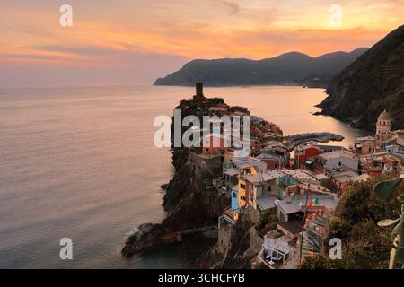 270 dramatischer, rot getönter Sonnenuntergang über den farbenfrohen Häusern der Stadt, die bis zum Meer reichen, und die Küste westwärts bis Punta Mesco Point. Vernazza-Ligurien Stockfoto