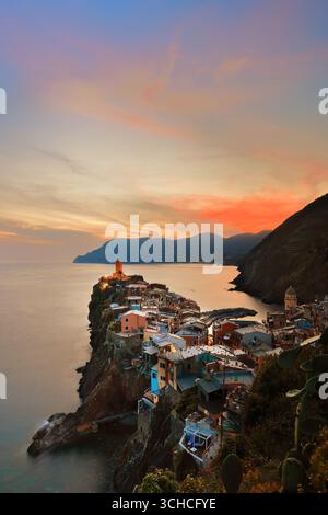271 dramatischer, rot getönter Sonnenuntergang über den farbenfrohen Häusern der Stadt, die bis zum Meer reichen, und die Küste westwärts bis Punta Mesco Point. Vernazza-Ligurien Stockfoto
