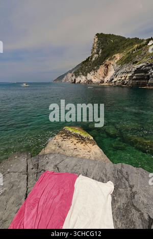 276 Badetücher - tiefrosa, cremeweiß - auf den Felsen rund um Cala dell'Arpaia Cove, Sitz der Grotta di Lord Byron Cave. Porto Venere-Ligurien. Stockfoto