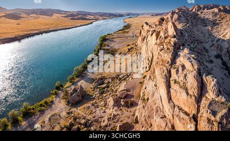 Panoramablick auf den Fluss Ili, der bei Sonnenuntergang durch Canyons und Wüstenlandschaft in Kasachstan fließt Stockfoto
