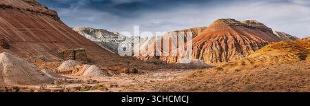 Panoramablick auf die farbenfrohen Berge, die sich aus der trockenen Wüstenlandschaft unter bewölktem Himmel in Kasachstan erheben Stockfoto