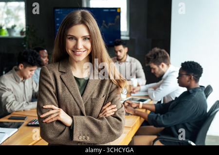 Junge Geschäftsfrau sitzt auf dem Schreibtisch und posiert Stockfoto