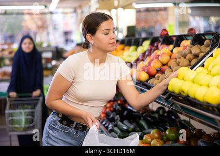 Eine junge Käuferin wählt Äpfel im Supermarkt Stockfoto