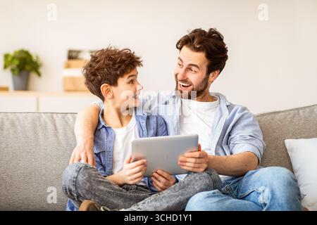 Familienwochenende. Vater und Sohn wurden mit einem Tablet-Computer excoted, surfte im Internet, während sie zu Hause Zeit miteinander verbrachten Stockfoto