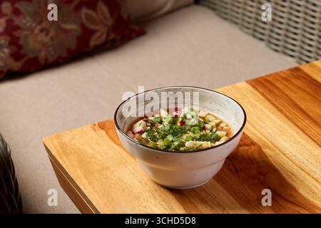 Köstliche asiatische Suppe, serviert in einer charmanten Schüssel auf einem rustikalen Holztisch Stockfoto