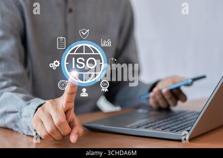 Qualitätssicherungs-, Zertifizierungs- und Qualitätssicherungskonzept gemäß ISO-Normen. Geschäftsmann mit Mobiltelefon mit Dokument und Qualitätszertifikat Stockfoto