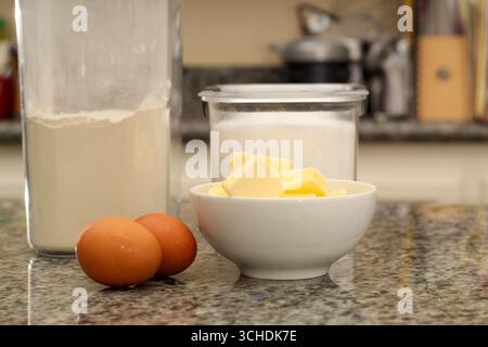 Zutaten für Eier, Mehl und Butter zum Backen auf Küchenarbeitsplatten Stockfoto