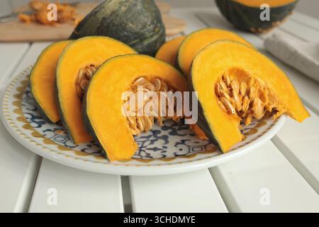 Stücke, Kürbisscheiben auf Porzellanplatte mit blauem Muster. Landwirtschaftliche Produkte und gesunde Ernährung. Küche und Hausmannskost. Stockfoto
