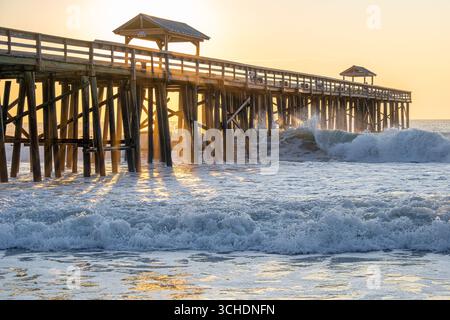 Sonnenaufgang am Amelia by the Sea Ocean Pier in Fernandina Beach, Florida, auf Amelia Island, während die Wellen eindringen und gegen die Pier-Anhäufungen krachen. (USA) Stockfoto