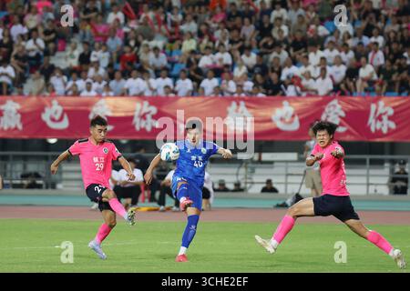 Spieler beider Teams kämpfen während des Spiels heftig. Zhenjiang, China, 31. August 2025. Die neue Runde der Jiangsu City Football League 2025 (Su Chao) begann am Abend des 31. August 2025 in der Stadt Zhenjiang, Provinz Jiangsu. Junge Fans schoben einen riesigen Fußball, um vor dem Spielbeginn eine Aufwärmphase zu machen, was eine lebhafte Atmosphäre auf dem Spielfeld schafft. Quelle: Yang Bo/China News Service/Alamy Live News Stockfoto