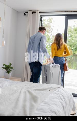 Ein Paar, das mit Koffer zu Hause geht, bereitet sich auf ein gemeinsames Reiseabenteuer vor Stockfoto